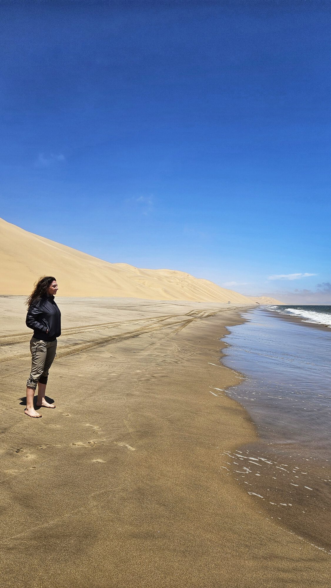 Kelly standing where the Namib Desert dunes meet the Atlantic Ocean