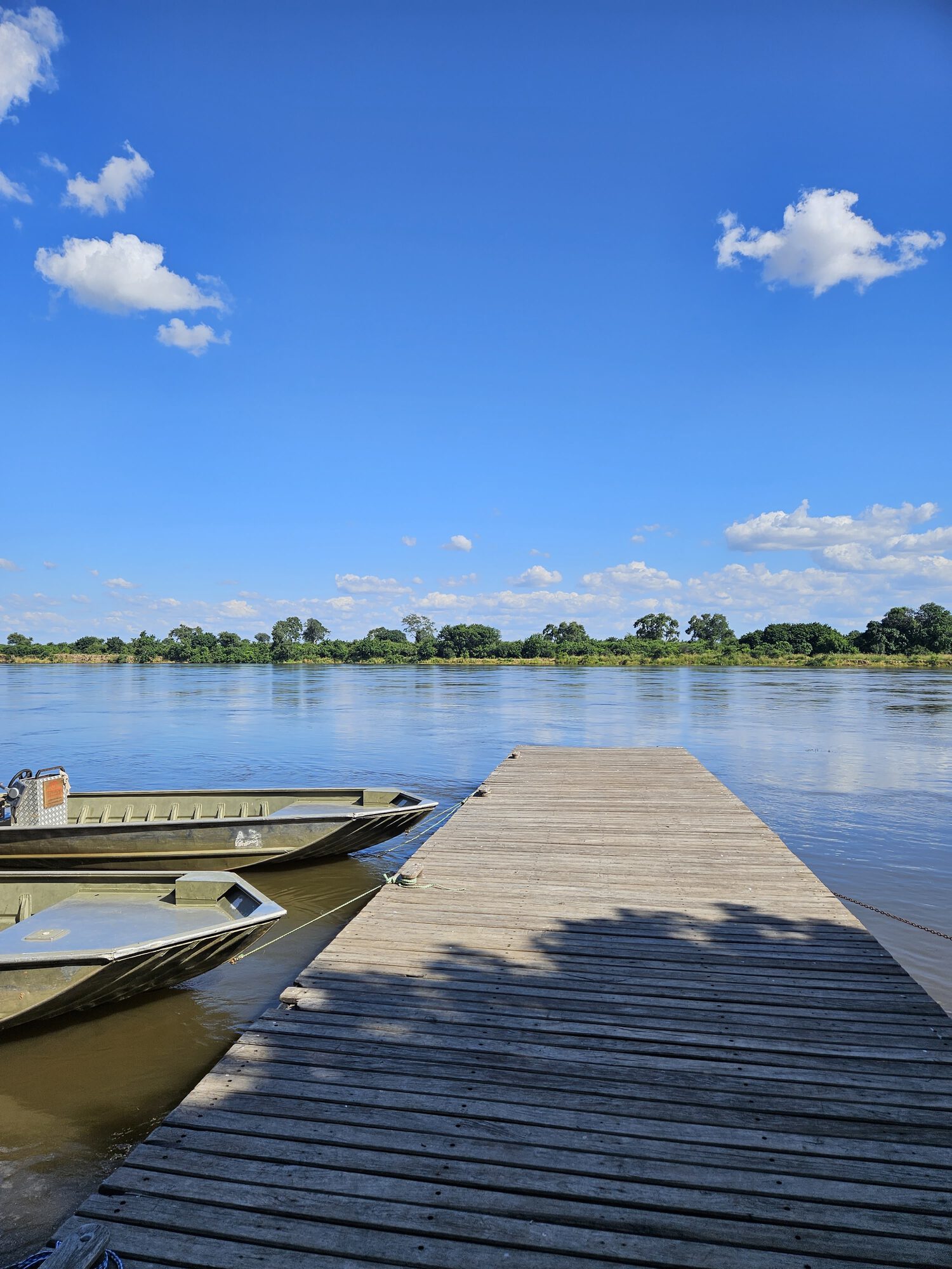 Wooden jetty extending into the calm Zambezi River on a clear Zambian morning
